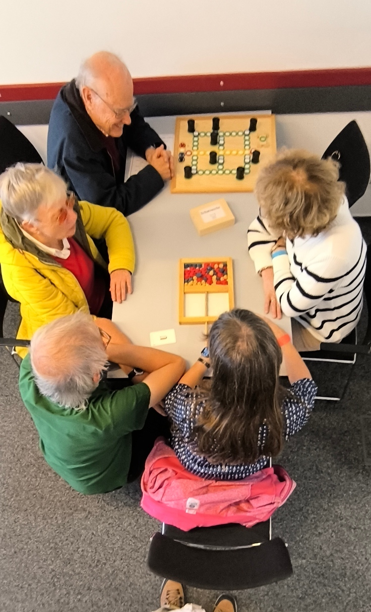 Die workshopleiter Wiedemann und 3 Gäste beim Ausprobieren von Spielen
